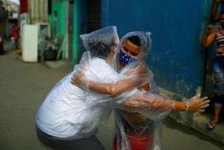 Teacher Maura Silva, who works for public school Escola Municipal Frei Vicente de Salvador and who created a "hug kit" using plastic covers, embraces her student Yuri Araujo Silva at Yuri's home, amid the coronavirus disease (COVID-19) outbreak, in the 77 Padre Miguel slum in Rio de Janeiro, Brazil July 23, 2020.