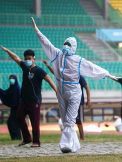 A health worker wearing protective suit and patients exercise at the Patriot Chandrabhaga Stadium which has been converted into a quarantine house amid the coronavirus disease (COVID-19) outbreak, in Bekasi, on the outskirts of Jakarta, Indonesia