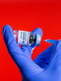 A woman holds a small bottle labeled with a "Coronavirus COVID-19 Vaccine" sticker and a medical syringe in front of displayed China flag in this illustration taken, October 30, 2020.