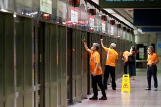 Workers wipe down doors at a train station during the coronavirus disease outbreak in Singapore on August 17, 2020.