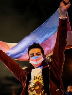 A demonstrator with a transgender pride flag and face mask looks on during a protest against the murders of transgender people in Colombia, in Bogota on July 3, 2020.