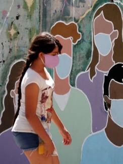 A girl wearing a face mask to prevent the spread of the coronavirus disease (COVID-19) walks past a graffiti in homage to the medical staff, at the San Martin hospital, in La Plata, on the outskirts of Buenos Aires, Argentina January 21, 2021.