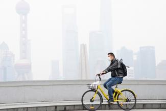 A man wearing a face mask rides a bicycle on a bridge in front of the financial district of Pudong covered in smog during a polluted day in Shanghai, China on November 22, 2017.