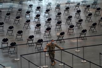 A National Guard soldier looks on as people stand in line at the Jacob K. Javits Convention Center Vaccination Center as Governor Andrew M. Cuomo announces the start of the statewide "Vaccinate NY" ad campaign to encourage all New Yorkers to get vaccinated, in New York City, New York, U.S. April 6, 2021.