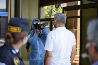 An employee with a thermal scanner checks the temperature of a man before he enters into a building