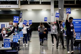 Workers hold up their station signs to signal they are ready for a patient at a coronavirus disease (COVID-19) vaccination site at Lumen Field Event Center in Seattle, Washington on March 13, 2021.