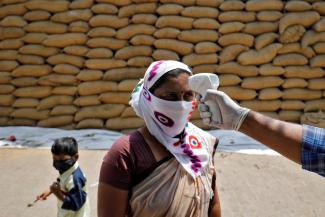  A healthcare worker checks the temperature of a rice mill worker during a coronavirus disease (COVID-19) vaccination drive at Bavla village on the outskirts of Ahmedabad, India, April 13, 2021. 