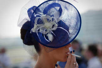 A spectator smokes a cigarette as she waits for the start of the Dubai World Cup horse race at Meydan Racecourse in Dubai, United Arab Emirates on March 29, 2014. REUTERS/Caren Firouz