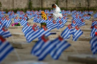 A cemetery worker puts flowers on the graves of people who died of the coronavirus disease (COVID-19) during The Day of the Dead celebration, as the outbreak continues, at La Bermeja cemetery in San Salvador, El Salvador November 2, 2020.