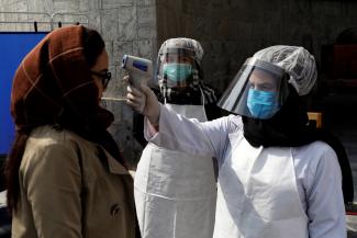 An Afghan health worker in protective gear checks the temperature of a woman before Afghanistan's President Ashraf Ghani inauguration as president, at the Presidential Palace in Kabul, Afghanistan March 9, 2020.