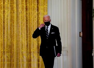 U.S. President Joe Biden removes his face mask as he arrives to deliver remarks on the COVID response and vaccination program at the White House, in Washington, DC, on August 18, 2021.