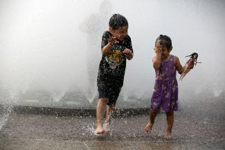 Children cool off in the Salmon Springs Fountain as a heat wave hits the Pacific Northwest in Portland, Oregon, U.S., July 30, 2021.