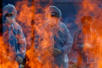 Relatives stand next to the burning pyre of a man who died from the coronavirus disease (COVID-19) during his cremation at a crematorium ground in Srinagar May 25, 2021.