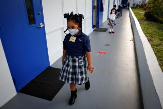 Students wearing a protective mask, queue up outside classrooms on the first day of school, amid the coronavirus disease (COVID-19) pandemic, at St. Lawrence Catholic School in North Miami Beach, Florida, U.S. August 18, 2021