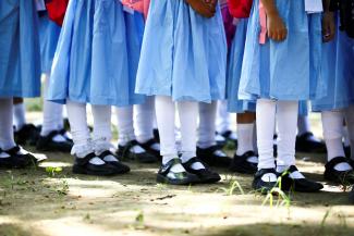 Students in blue dresses, white stockings, and black shoes stand in queues at the Viqarunnisa Noon School & College, in Dhaka, Bangladesh, September 12, 2021. 