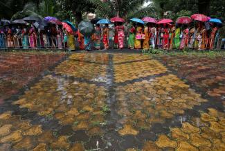 Women hold umbrellas to cover from rain as they wait to receive a dose of COVISHIELD vaccine, a COVID-19 vaccine made by Serum Institute of India, at a vaccination centre in Kolkata, India, August 31, 2021. 