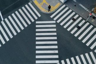 A man waits to cross a street in front of Shinjuku Station, a normally crowded street during the weekend, after the government expanded a state of emergency to include the entire country last week following the coronavirus disease (COVID-19) outbreak, in Tokyo, Japan, April 19, 2020.