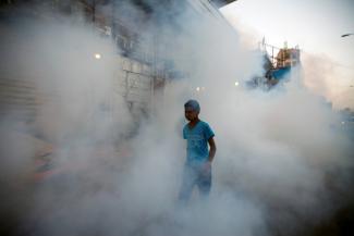 A boy is seen among smoke while public health workers spray insecticide amid fears of a new cholera outbreak in Sanaa, Yemen, on June 7, 2018. 