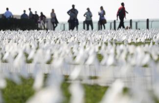 People wander through a COVID memorial made of 26,661 white flags at the Griffith Observatory in Los Angeles, California, on November 20, 2021. 