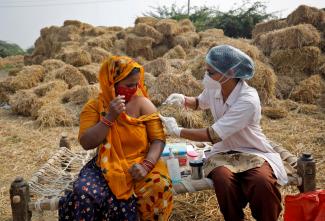 A woman receives a dose of COVISHIELD vaccine against COVID-19, that's manufactured by Serum Institute of India, while working in a field during a door-to-door vaccination drive at Mahijada village on the outskirts of Ahmedabad, India, December 15, 2021