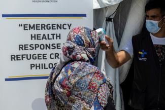 A health ministry official gets the temperature of a migrant before receiving the Johnson & Johnson vaccine against COVID-19 in the Mavrovouni camp on the island of Lesbos, Greece, on June 3, 2021. 