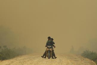 Villagers ride a motorcycle in a haze hit Dumai, in Indonesia's Riau province June 21, 2013. Hospitals in Dumai and Bengkalis in Indonesia's Riau province recorded increases in cases of asthma, lung, eye and skin problems, said health official Arifin Zainal.