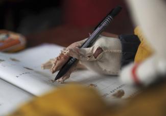 A boy, suffering from an extensive burn injury, holds a pencil to write during a lesson inside his the classroom at a primary school in Zhuanji town, Anhui province, China, on November 15, 2011.