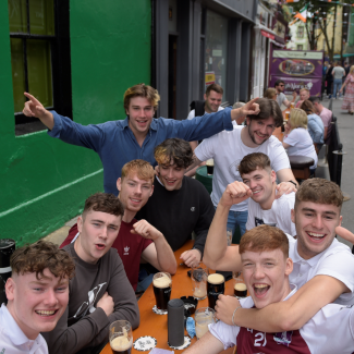 A group of friends celebrates at an outdoor table, drinking beers, laughing, and cheering as COVID-19 restrictions ease in Galway, Ireland, on June 7, 2021.