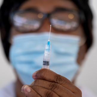 A close-up photo of a health worker wearing a mask as she prepares a syringe with a dose of Moderna's COVID-19 vaccine at Saint Damien Hospital in Port-au-Prince, Haiti, on July 19, 2021.