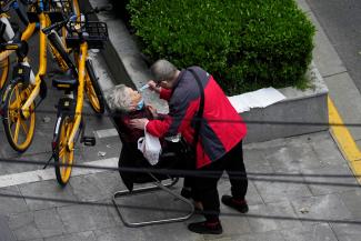 A man helps a woman to consume a packet of traditional Chinese medicine (TCM) Lianhua Qingwen, as she sits by the side of a road outside a residential compound, during a lockdown to curb the spread ofCOVID-19 in Shanghai, China April 5, 2022.