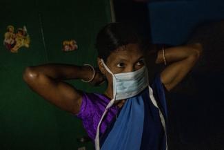 a health worker, puts on a protective face mask as she gets ready to travel to Mathalput Community Health Centre