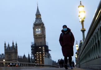 A masked pedestrian walks over Westminster Bridge in London, on January 27, 2022