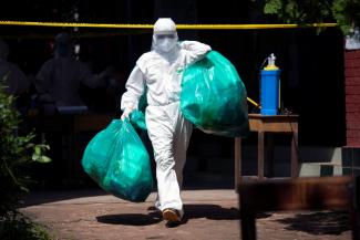 A medical worker wearing a personal protective suit carries green plastic bags with medical waste at a quarantine center amid the COVID-19 outbreak in Yangon, Myanmar, October 7, 2020. 