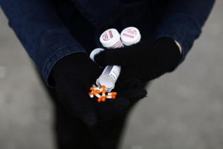 A fentanyl user in a denim jacket and black gloves displays their "safe supply" of opioid alternatives in Vancouver, Canada, April 6, 2020
