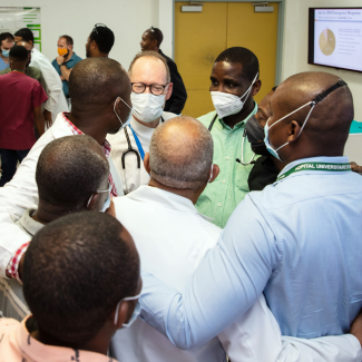 Paul Farmer hugs colleagues in Haiti. While helping with the response to the August 14, 2021, earthquake, Dr. Paul Farmer gives a lecture on the 2010 Haiti earthquake and speaks with clinicians at Hopital University de Mirebalais.