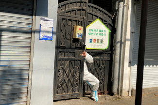 A person in a protective suit squeezes through a locked gate of a residential compound, during a COVID-19 outbreak and lockdown in Shanghai, China, on April 21, 2022. 