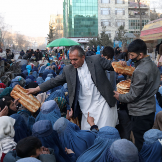 Mehr del Khan Rahmati, who is in charge of a bakery, passes bread to people awaiting food in Kabul, Afghanistan, on January 31, 2022. REUTERS/Ali Khara