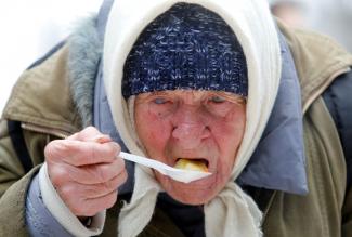 An elderly woman eats a meal during a charity event that provided food to lower-income citizens in a cathedral compound in Stavropol, Russia, on December 13, 2019. 