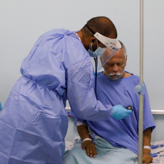 A physician with Doctors Without Borders (MSF) places his stethoscope on the chest of hospital patient Marco Vargas, who has COVID, in Caracas, Venezuela, on February 1, 2022. 