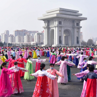 Hundreds of women dressed in pink and white traditional North Korean gowns stand in rows in a central area of Pyongyang, North Korea, on Women's Day in March 2022.