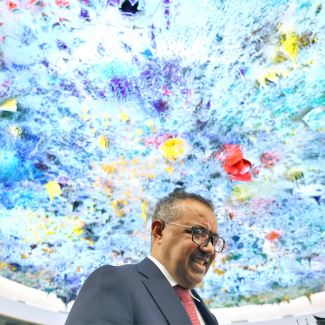 A blue, purple, and yellow skylight hovers above Dr. Tedros Adhanom Ghebreyesus, director-general of the World Health Organization (WHO) celebrates his re-election during the 75th World Health Assembly at the United Nations in Geneva, Switzerland, May 24, 2022. 