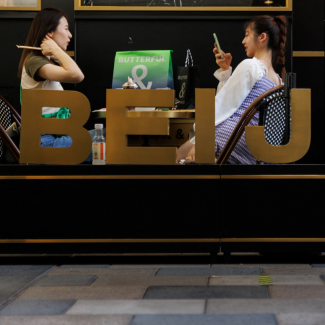 Two women relax in a cafe behind a sign with large letters spelling out Beijing, in a shopping area in Beijing, China, on July 14, 2022. 