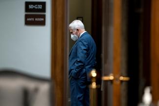 Dr. Anthony Fauci is pictured wearing a dark blue suit and white N-95 facemask ahead of a senate hearing on Capitol Hill