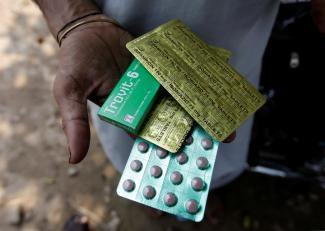 A tuberculosis patient holds his medicines received from the government's tuberculosis center in Rawalpindi, Pakistan July 11, 2016. The pink pills are sealed in rows of green packaging with gold foil on the back that gives the name and dosage of the drug.