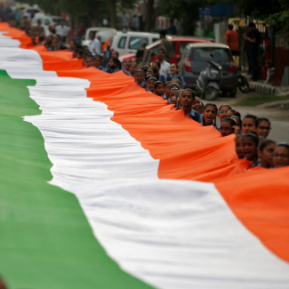 Students hold a giant Indian national flag with green, white and orange stripes, during celebrations commemorating 75 years of India's Independence, in Ahmedabad, India, August 8, 2022. 