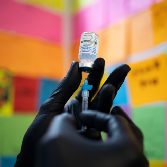 The black-gloved hand of Dr. Mayank Amin prepares a Moderna COVID booster vaccine targeting BA.4 and BA.5 omicron subvariants, at Skippack Pharmacy in Schwenksville, Pennsylvania, September 8, 2022. 