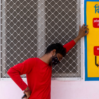 A man in a red shirt stands in profile and weeps as his mother is being treated inside a COVID-19 intensive care unit of a government-run hospital, amidst the coronavirus pandemic, in Bijnor District, Uttar Pradesh, India, on May 11, 2021. Photo by REUTERS/Danish Siddiqui