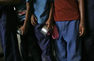 School boys carry their tiffin boxes as they wait to receive their free midday meal, distributed by a government-run primary school, in New Delhi, India, on July 19, 2013. 