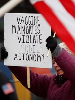A protester holds a banner at a rally against mandates for the vaccines against the coronavirus disease (COVID-19) outside the New York State Capitol in Albany, New York.