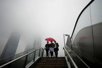 People wearing masks walk on an overpass at Lujiazui financial district, as